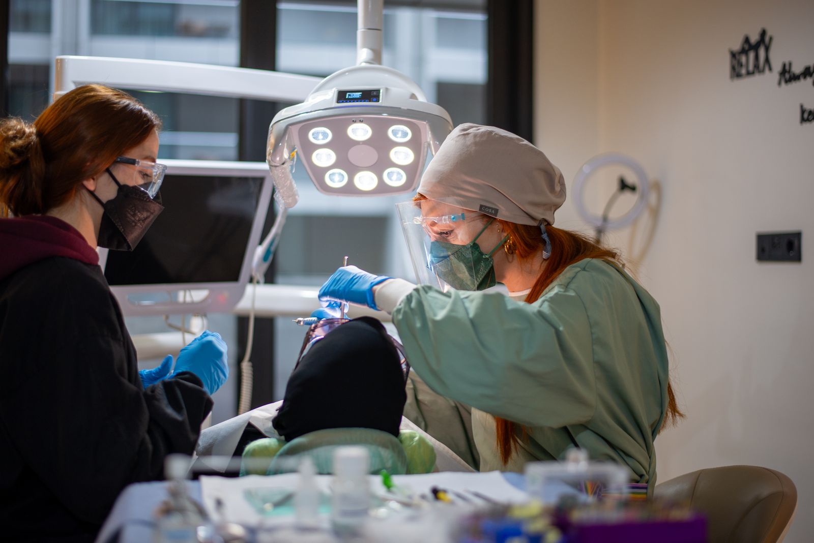 Dentista realizando procedimento dental com assistente em ambiente clínico moderno.
